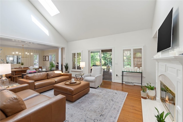 1413 Oak St, Oakmont, PA 15139 - living area featuring wood finished floors, a premium fireplace, healthy amount of natural light, high vaulted ceiling, and a chandelier