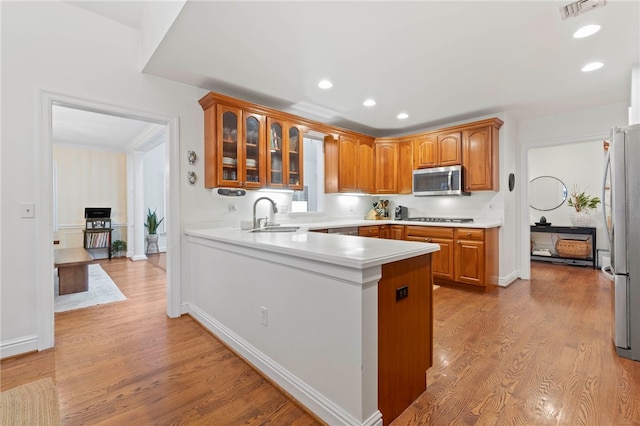 1413 Oak St, Oakmont, PA 15139 - kitchen featuring appliances with stainless steel finishes, a peninsula, glass insert cabinets, light wood-style flooring, and recessed lighting