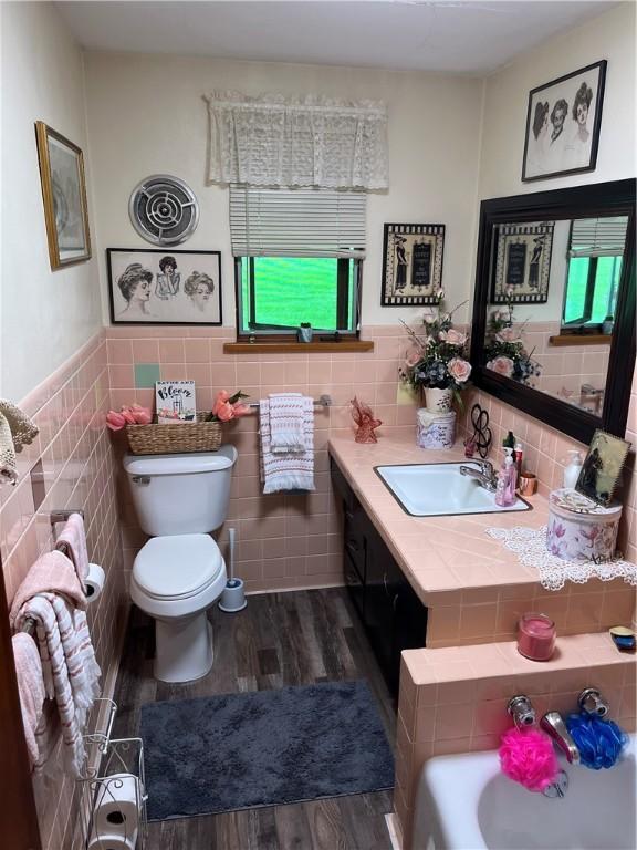 3015 Graham Ave, Windber, PA 15963 - full bath with wood finished floors, tile walls, vanity, a bathtub, and a wainscoted wall