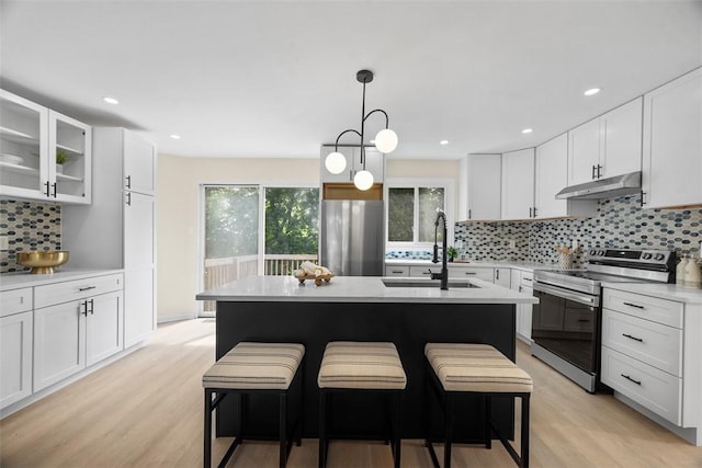 1014 Olga St, Ambridge, PA 15003 - kitchen with stainless steel appliances, under cabinet range hood, backsplash, light countertops, and light wood finished floors