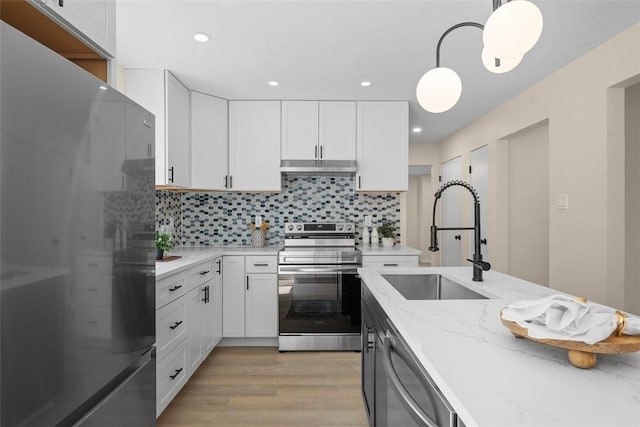 1014 Olga St, Ambridge, PA 15003 - kitchen featuring appliances with stainless steel finishes, white cabinetry, light wood-style flooring, pendant lighting, and light stone countertops