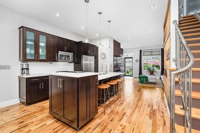 611 Suismon St, East Allegheny, PA 15212 - kitchen with appliances with stainless steel finishes, light wood-style flooring, light countertops, a kitchen bar, and recessed lighting