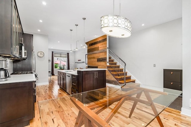611 Suismon St, East Allegheny, PA 15212 - kitchen featuring dark brown cabinets, light wood-type flooring, appliances with stainless steel finishes, a center island with sink, and light countertops