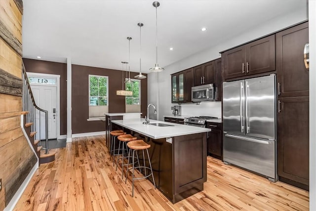 611 Suismon St, East Allegheny, PA 15212 - kitchen with appliances with stainless steel finishes, light countertops, light wood finished floors, a kitchen island with sink, and dark brown cabinets