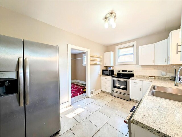 213 N 5th St, Jeannette, PA 15644 - kitchen featuring stainless steel appliances, white cabinets, plenty of natural light, and light countertops