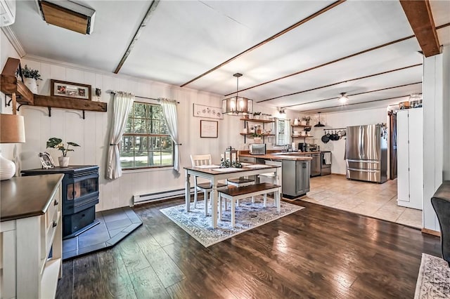 8995 Puritan Ln, Conneaut Twp, PA 16424 - dining space featuring a baseboard radiator, wood finished floors, a wood stove, and an AC wall unit