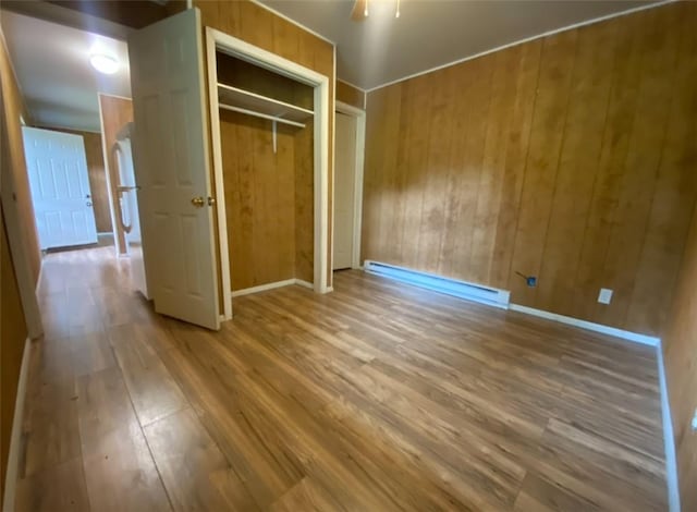 377 Mercer Rd, Hempfield Twp, PA 16125 - unfurnished bedroom with wood finished floors, wooden walls, a baseboard heating unit, a closet, and ceiling fan