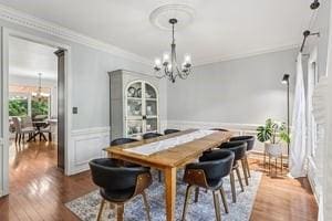 403 Worth Ct, Cranberry Twp, PA 16066 - dining space featuring a chandelier, crown molding, dark wood finished floors, and a wainscoted wall