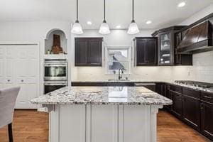 403 Worth Ct, Cranberry Twp, PA 16066 - kitchen featuring appliances with stainless steel finishes, extractor fan, a kitchen island, light stone countertops, and glass insert cabinets