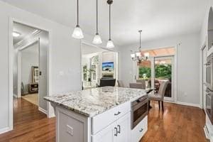403 Worth Ct, Cranberry Twp, PA 16066 - kitchen with a chandelier, light stone countertops, stainless steel microwave, dark wood-type flooring, and a kitchen island