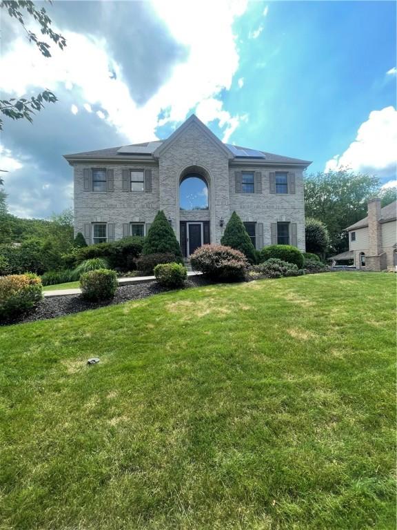 403 Worth Ct, Cranberry Twp, PA 16066 - view of front facade with stone siding, a front yard, and roof mounted solar panels