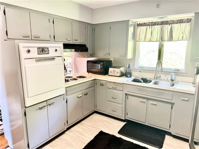 110 Surrey St, Monessen, PA 15062 - kitchen with white appliances, gray cabinetry, under cabinet range hood, and light countertops