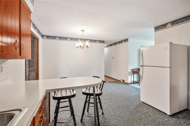 4852 Thomason Rd, South Pymatuning Twp, PA 16150 - kitchen with freestanding refrigerator, wallpapered walls, a chandelier, brown cabinets, and a breakfast bar