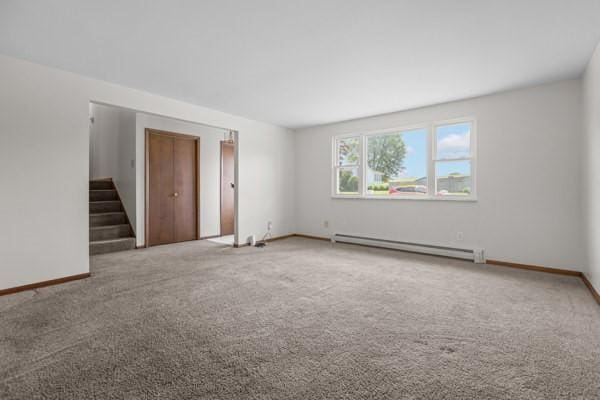 408 Circle Dr, Franklin Twp, PA 16117 - carpeted empty room with a baseboard radiator and stairway