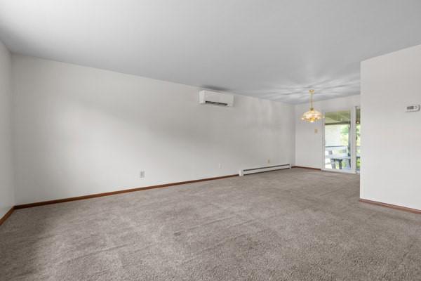 408 Circle Dr, Franklin Twp, PA 16117 - spare room featuring a wall mounted air conditioner, baseboard heating, and carpet