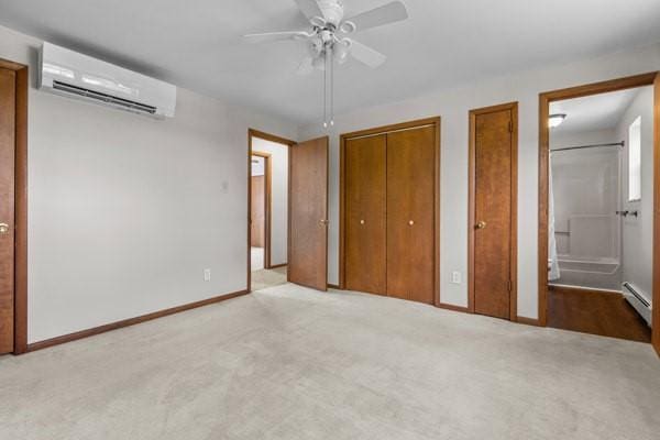 408 Circle Dr, Franklin Twp, PA 16117 - unfurnished bedroom featuring an AC wall unit, carpet, two closets, baseboard heating, and ensuite bathroom