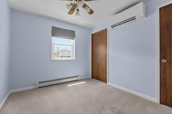 408 Circle Dr, Franklin Twp, PA 16117 - unfurnished bedroom featuring a baseboard radiator, a wall mounted AC, carpet, and ceiling fan
