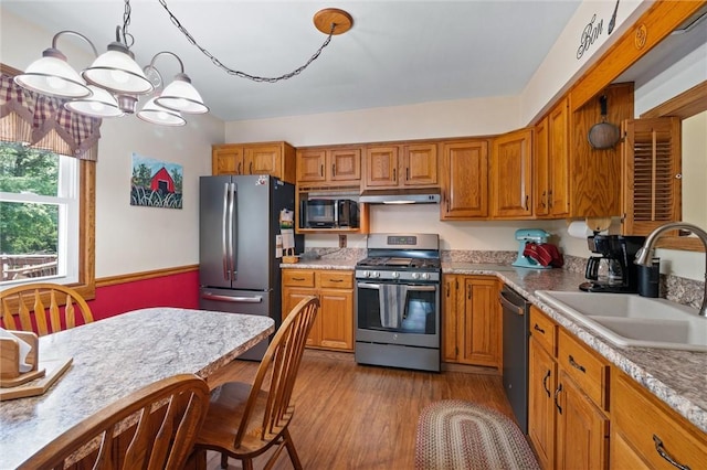 817 E Jamestown Rd, Green Twp, PA 16134 - kitchen with stainless steel appliances, under cabinet range hood, brown cabinets, and a chandelier
