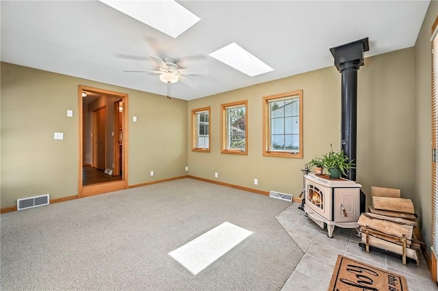 2801 Valley View Rd, South Pymatuning Twp, PA 16150 - unfurnished room featuring a wood stove, a skylight, a ceiling fan, light carpet, and light tile patterned floors