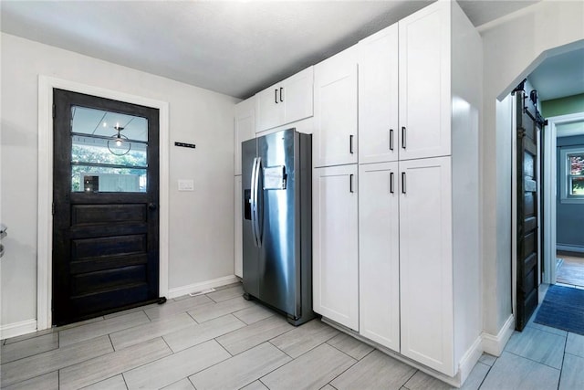115 Muddy Creek Dr, Center Twp, PA 16001 - kitchen with stainless steel fridge with ice dispenser, white cabinetry, a barn door, and wood tiled floors