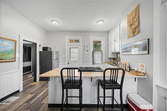 11 Walnut St, Crafton, PA 15205 - kitchen with a peninsula, white cabinetry, dark wood-type flooring, appliances with stainless steel finishes, and a breakfast bar area