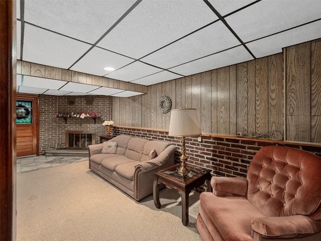 823 Clearview Dr, Penn Hills, PA 15147 - living room with a paneled ceiling, carpet flooring, a brick fireplace, and wood walls