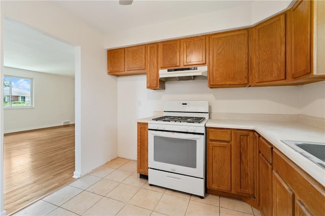 6623 Rosemoor St, Squirrel Hill, PA 15217 - kitchen featuring under cabinet range hood, white gas stove, brown cabinetry, light countertops, and light tile patterned floors