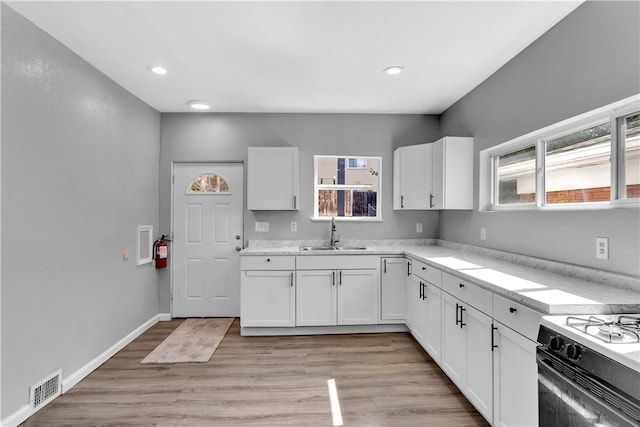 1406 Broadway Ave, Stowe Twp, PA 15136 - kitchen with white cabinetry, light countertops, light wood finished floors, recessed lighting, and gas range
