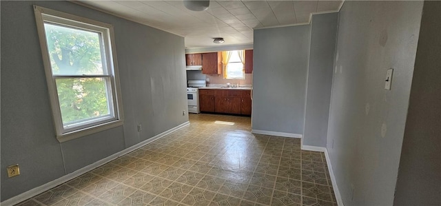 705 Carlisle St, New Castle, PA 16101 - kitchen featuring white gas stove, light flooring, light countertops, under cabinet range hood, and brown cabinets
