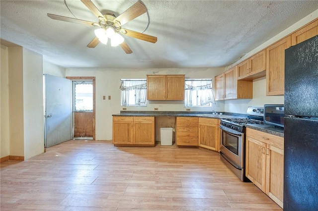 75 Wilson St, Etna, PA 15223 - kitchen with freestanding refrigerator, stainless steel gas range, light wood finished floors, dark countertops, and ceiling fan