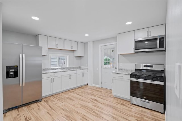1106 Wade St, Aliquippa, PA 15001 - kitchen with stainless steel appliances, white cabinetry, light wood finished floors, recessed lighting, and light stone countertops