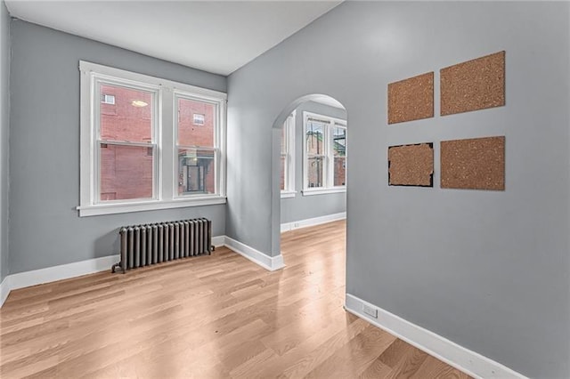 375 Main St, Lawrenceville, PA 15201 - spare room featuring radiator, arched walkways, light wood-style floors, and lofted ceiling