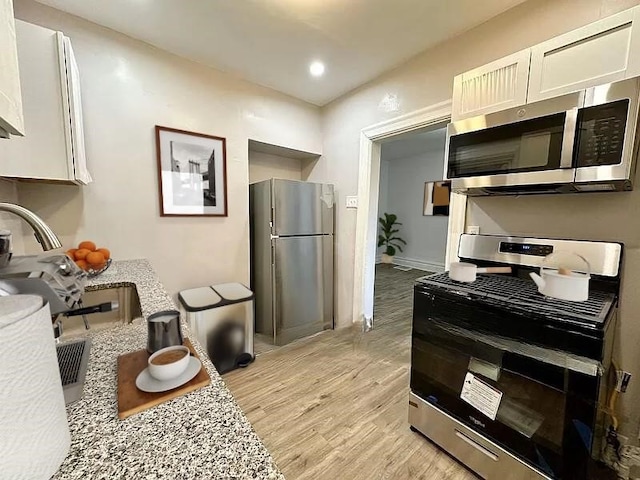 5404 Black St, Garfield, PA 15206 - kitchen featuring appliances with stainless steel finishes, light wood finished floors, white cabinets, recessed lighting, and light countertops
