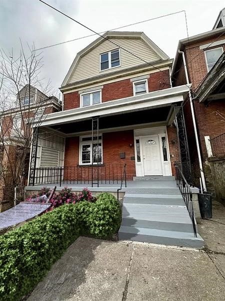 5404 Black St, Garfield, PA 15206 - view of front of house with a gambrel roof, brick siding, and a porch