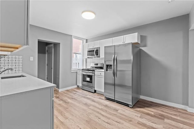 363 44th St, Lawrenceville, PA 15201 - kitchen with stainless steel appliances, backsplash, light countertops, light wood-style flooring, and white cabinetry