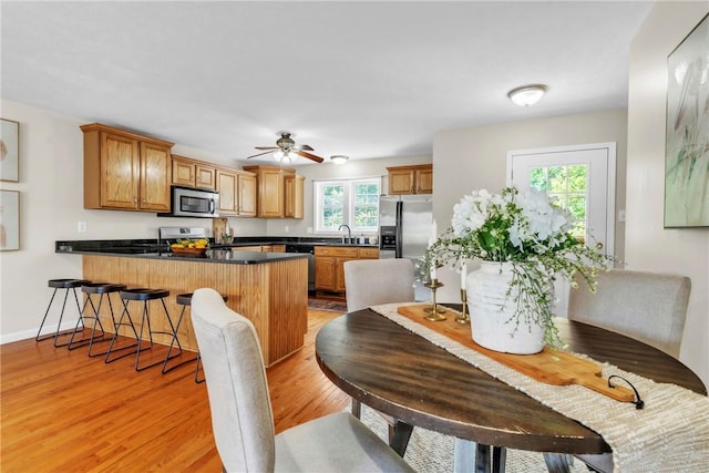 1109 Mary Ann, South Side, PA 15203 - kitchen featuring appliances with stainless steel finishes, a peninsula, dark countertops, light wood-type flooring, and brown cabinets