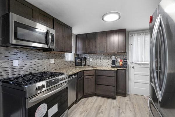 147 Rodilin Dr, Penn Hills, PA 15235 - kitchen featuring stainless steel appliances, light wood-style flooring, dark brown cabinets, decorative backsplash, and light stone counters