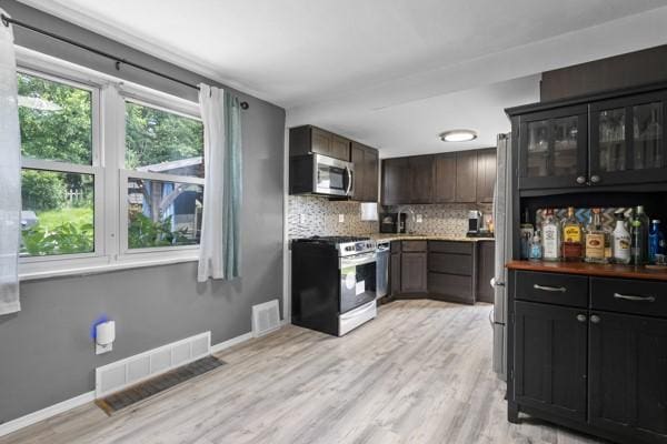 147 Rodilin Dr, Penn Hills, PA 15235 - kitchen with stainless steel appliances, decorative backsplash, light wood finished floors, glass insert cabinets, and light countertops