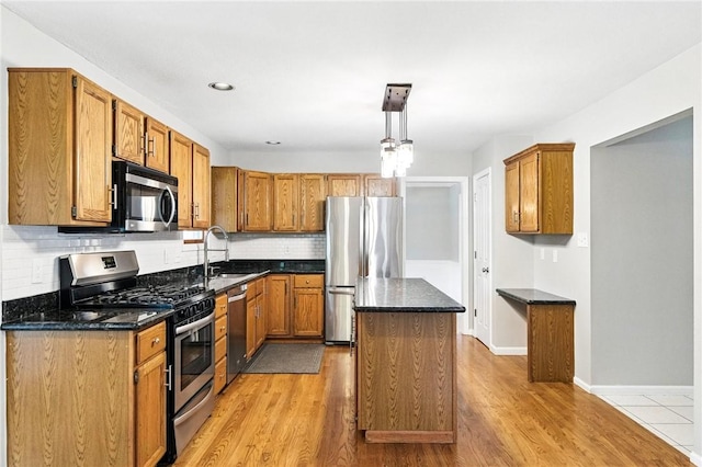 109 Hamilton Ct, Economy, PA 15005 - kitchen with appliances with stainless steel finishes, a center island, backsplash, brown cabinets, and light wood finished floors