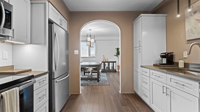 128 N Craig St Unit 505, Oakland, PA 15213 - kitchen with stainless steel appliances, dark wood-style floors, arched walkways, and white cabinetry