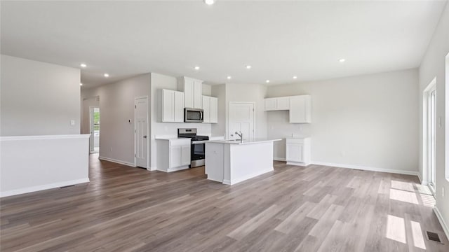 163 Smith Ln, Chippewa Twp, PA 15010 - kitchen with stainless steel appliances, open floor plan, white cabinets, an island with sink, and wood finished floors