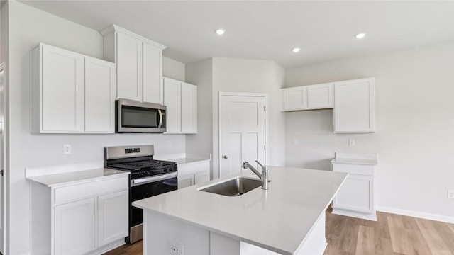 163 Smith Ln, Chippewa Twp, PA 15010 - kitchen featuring appliances with stainless steel finishes, a kitchen island with sink, white cabinets, light wood-style floors, and light countertops