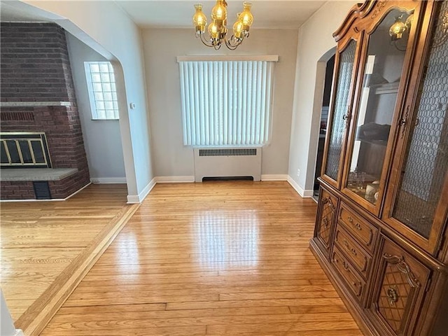 1606 Maryland Ave, West Mifflin, PA 15122 - entrance foyer with radiator, arched walkways, light wood-style floors, a chandelier, and a brick fireplace