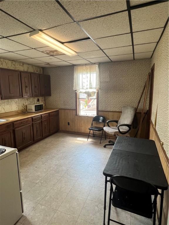 306 Fallowfield Ave, Charleroi Boro, PA 15022 - kitchen with range, wallpapered walls, light flooring, a paneled ceiling, and a wainscoted wall