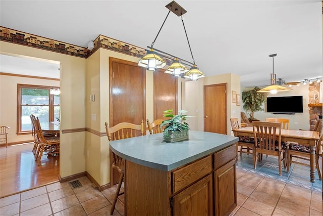 4581 Bakerstown Culmerville Rd, West Deer, PA 15044 - kitchen with a kitchen island, hanging light fixtures, light tile patterned flooring, and brown cabinets
