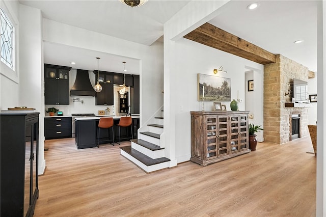 3901 Bakerstown Rd, Richland, PA 15044 - kitchen with custom exhaust hood, light wood-style flooring, a breakfast bar area, light countertops, and beam ceiling