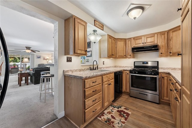 1417 Riverview Dr, Verona, PA 15147 - kitchen featuring stainless steel gas range, under cabinet range hood, black dishwasher, ceiling fan, and wood finished floors