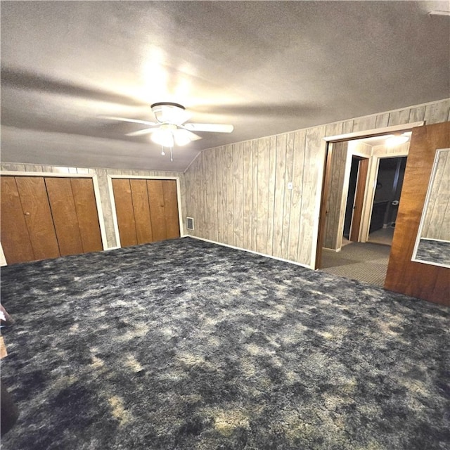76 Foch Cir, Nemacolin, PA 15351 - unfurnished bedroom with carpet flooring, two closets, wood walls, a ceiling fan, and a textured ceiling
