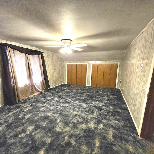 76 Foch Cir, Nemacolin, PA 15351 - unfurnished bedroom with carpet floors, wood walls, two closets, a textured ceiling, and ceiling fan