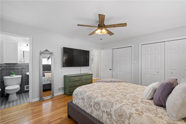 2633 Cedarvue Dr, Saint Clair, PA 15241 - bedroom with two closets, light wood-type flooring, ensuite bathroom, tile walls, and ceiling fan